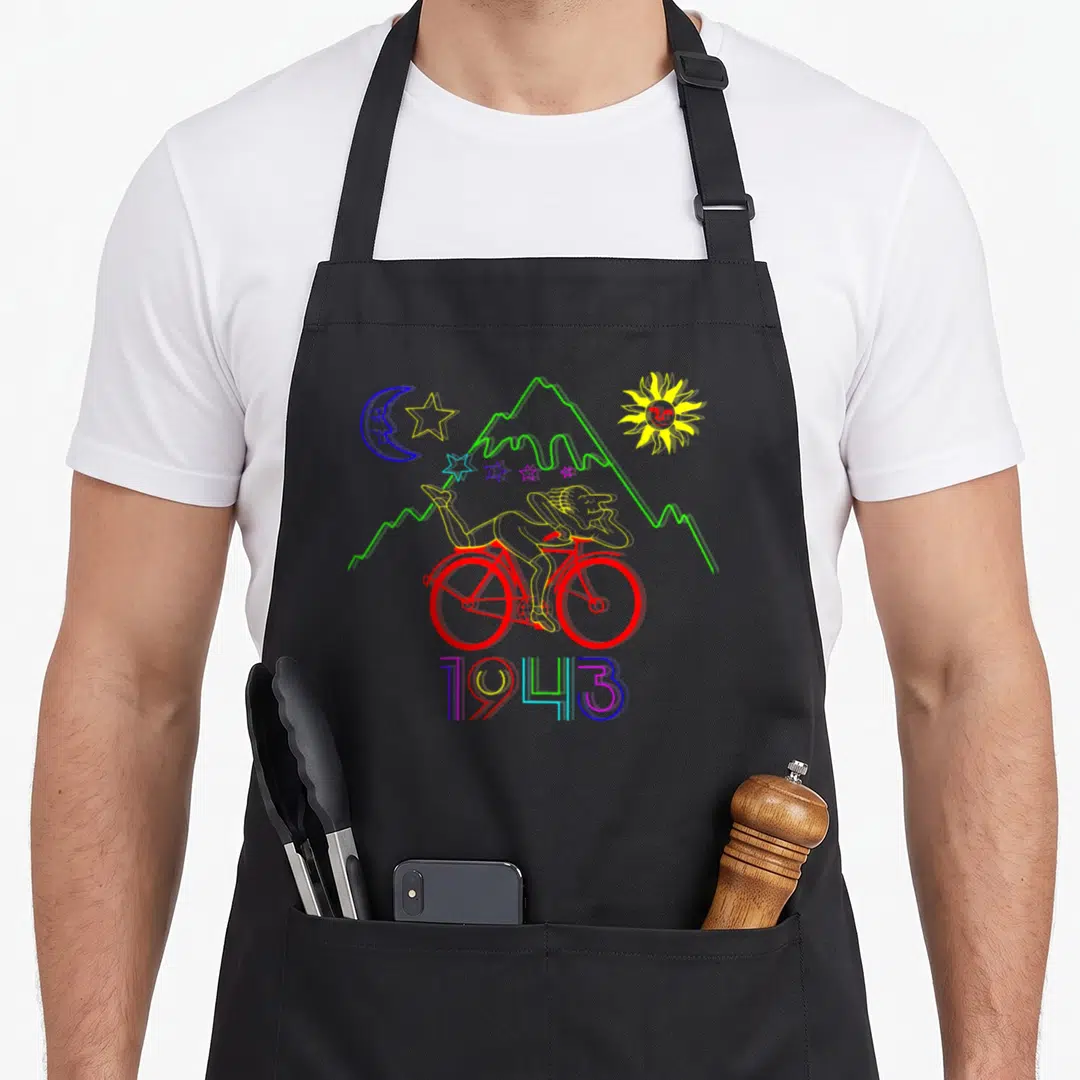 Creator bicycle apron - Line art of person on red bike under moon sun and stars with 1943 text — shown on a black cotton canvas apron against a white background