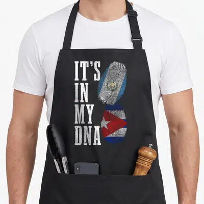 Cuba guatemalan aprons - IT'S IN MY DNA text beside two fingerprints filled with El Salvador and Cuba flag colors — shown on a black cotton canvas apron against a white background