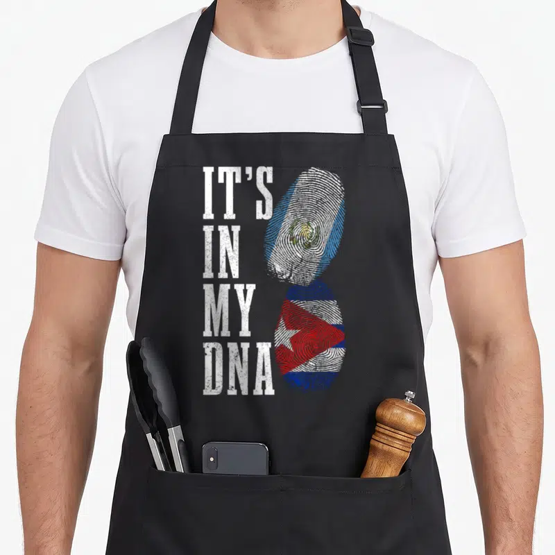 Cuba guatemalan aprons - IT'S IN MY DNA text beside two fingerprints filled with El Salvador and Cuba flag colors — shown on a black cotton canvas apron against a white background