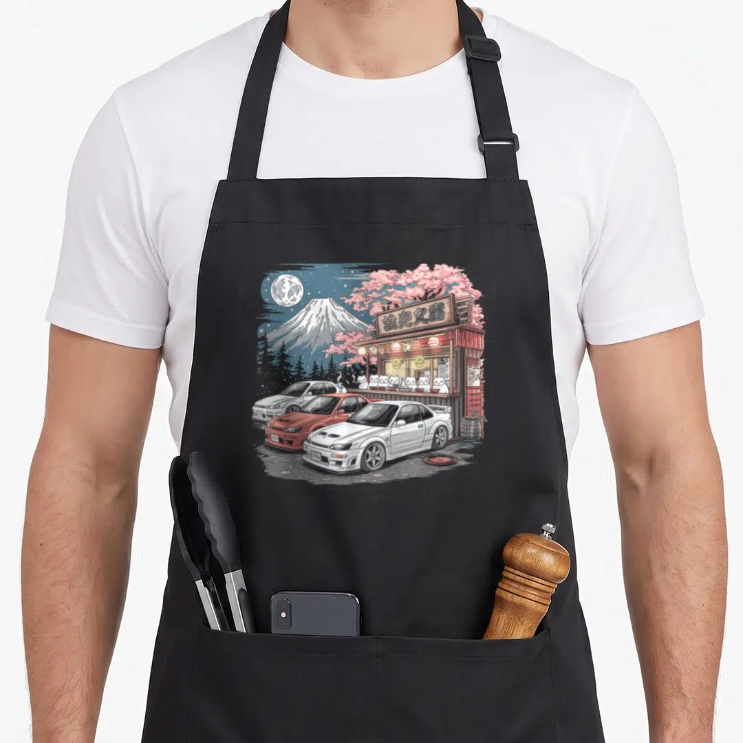 Streetwear japan apron - Three cars parked near a food stall with cats and a cherry blossom tree under a moonlit — shown on a black cotton canvas apron against a white background