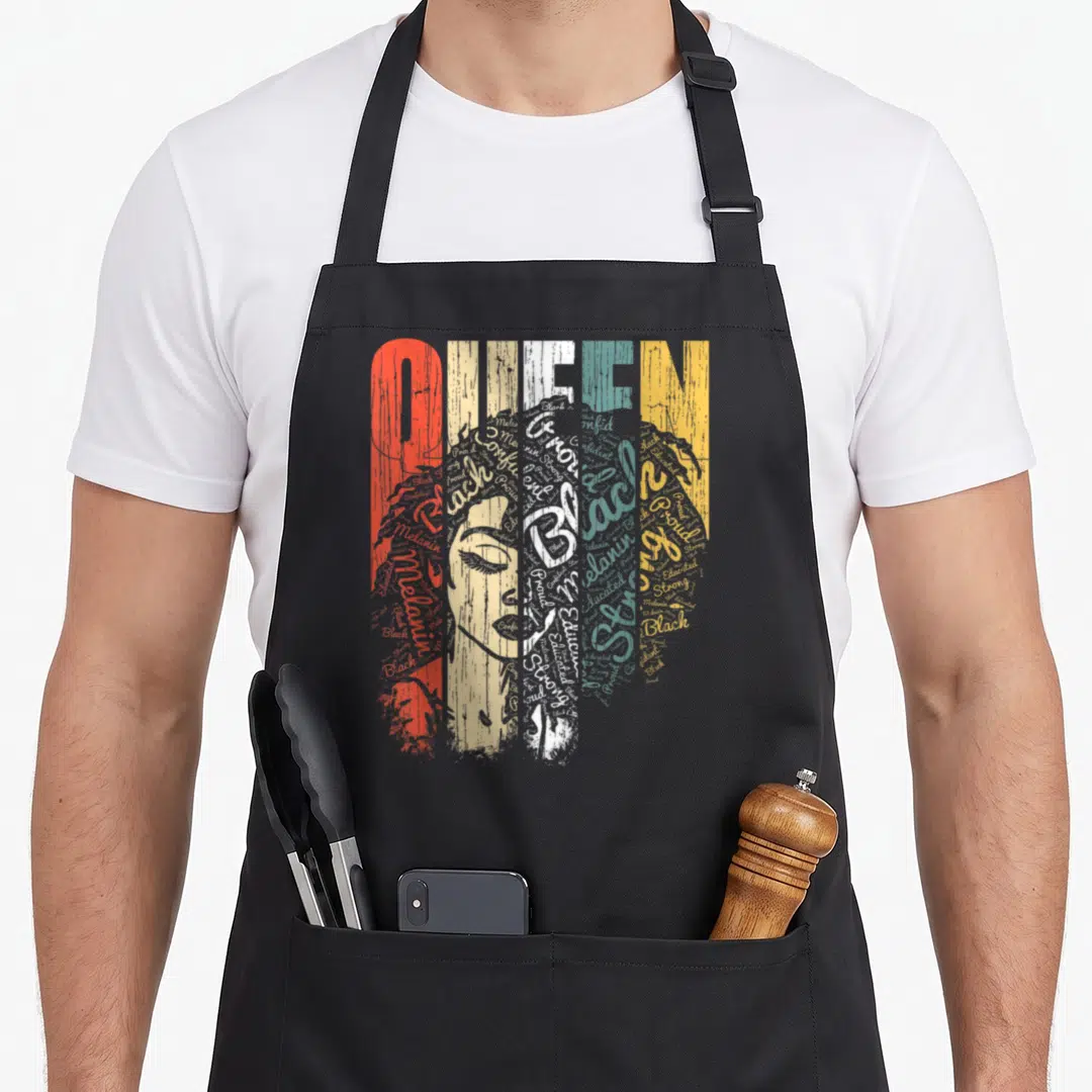 Queen african apron - Distressed QUEEN text and woman portrait formed by words Black Proud Strong Educated Confident — shown on a black cotton canvas apron against a white background