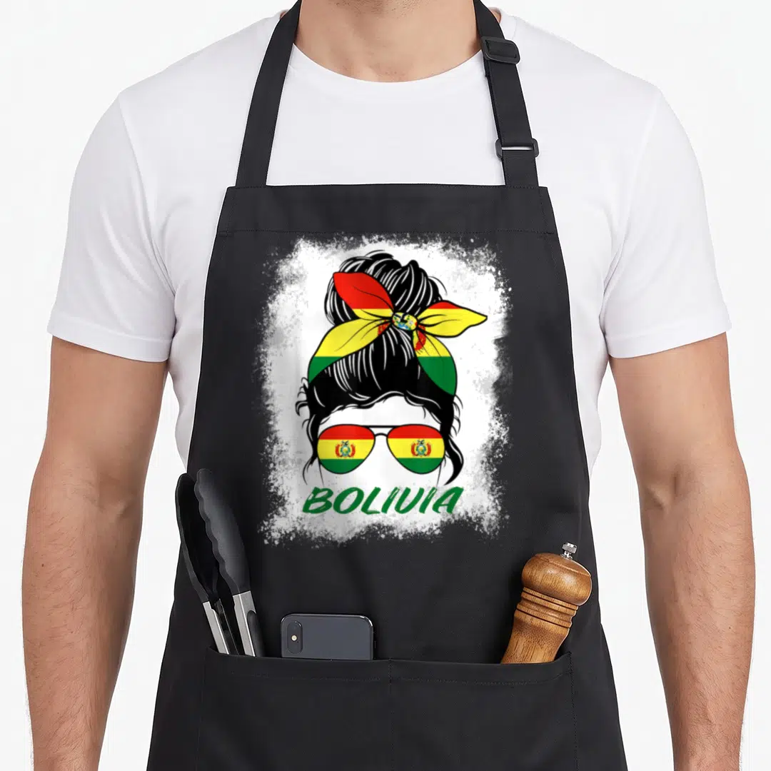 Bleached bolivian girl apron - Woman silhouette with bun, flag sunglasses, and BOLIVIA text on white splatter — shown on a black cotton canvas apron against a white background