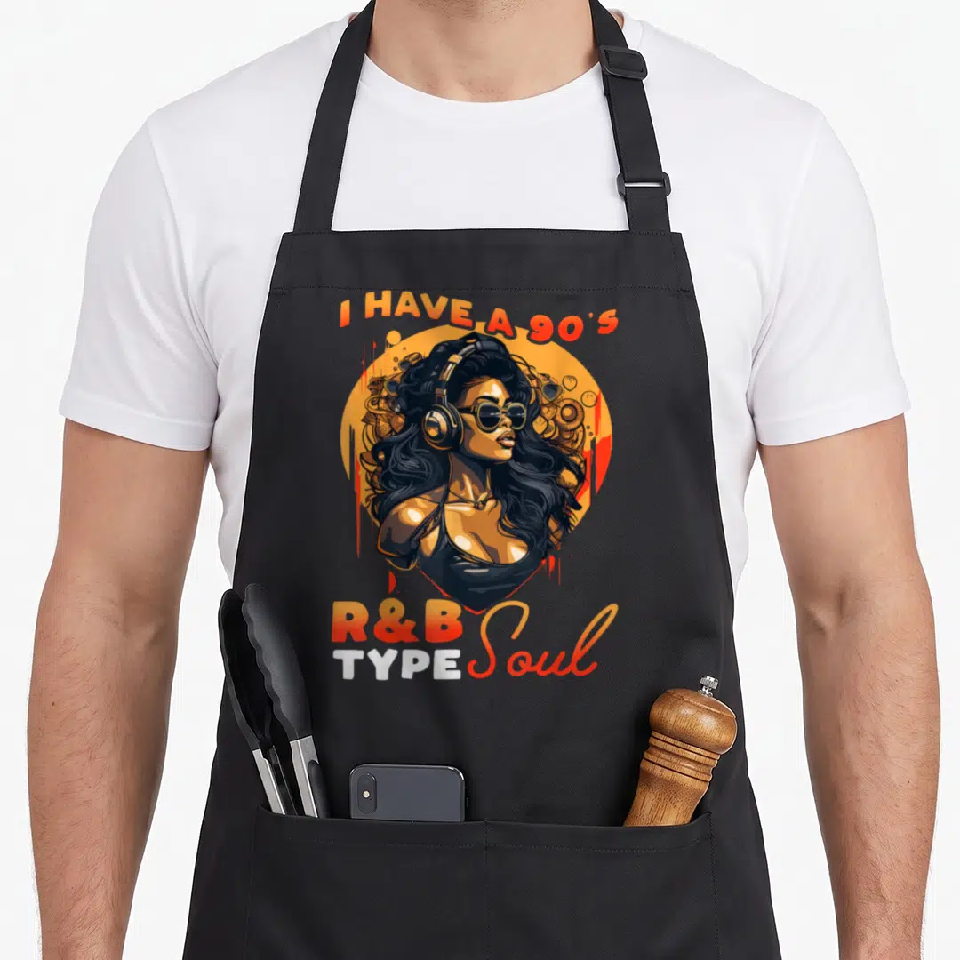 Soul r aprons - Cartoon woman with headphones in orange circle surrounded by I HAVE A 90S R&B TYPE Soul text — shown on a black cotton canvas apron against a white background