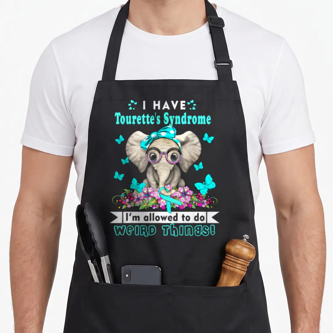 Vintage syndrome tourette awareness apron - Elephant in glasses and bandana surrounded by butterflies, flowers, ribbon — shown on a black cotton canvas apron against a white background