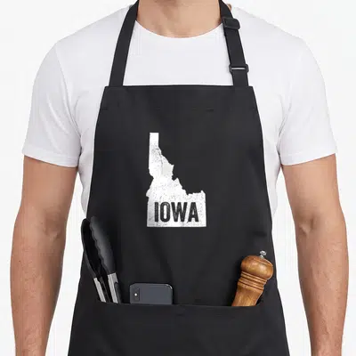 Idaho midwest apron - White Idaho map silhouette with IOWA text in distressed style — shown on a black cotton canvas apron against a white background