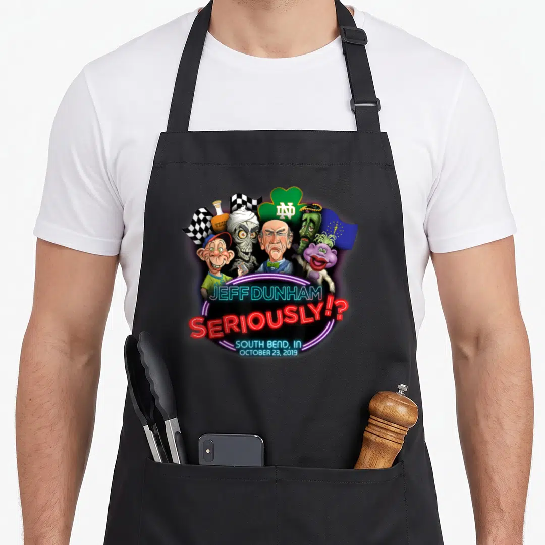 Jeff south boy apron - Neon Jeff Dunham text below a group of cartoon ventriloquist puppets and symbols including — shown on a black cotton canvas apron against a white background