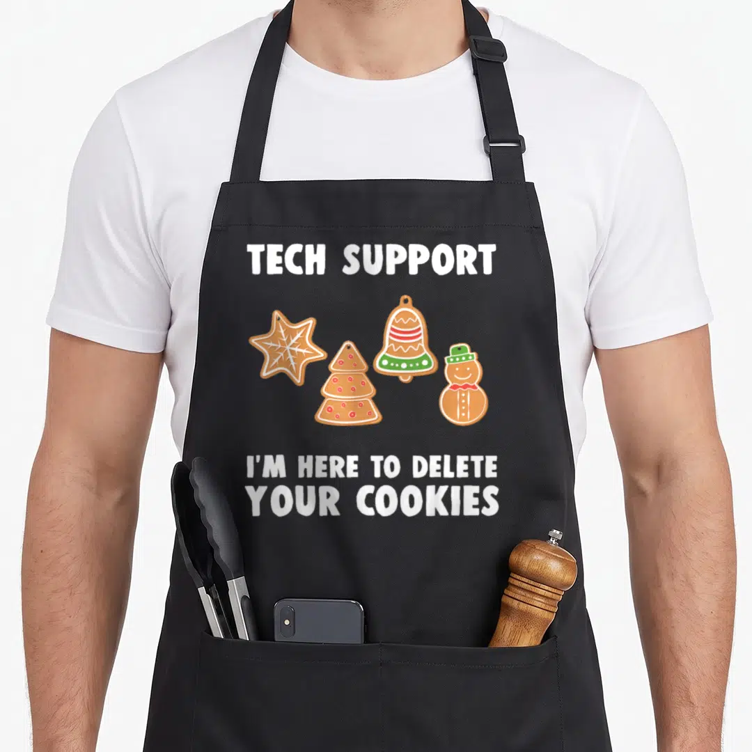 Tech christmas apron - Four gingerbread cookies with tech support delete cookies text — shown on a black cotton canvas apron against a white background