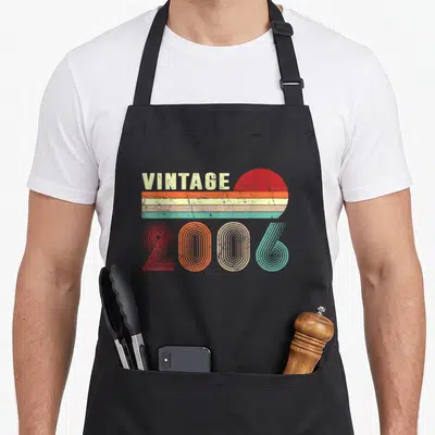 20th birthday apron - Vintage 2006 retro text over red sun and beige teal orange stripes — shown on a black cotton canvas apron against a white background