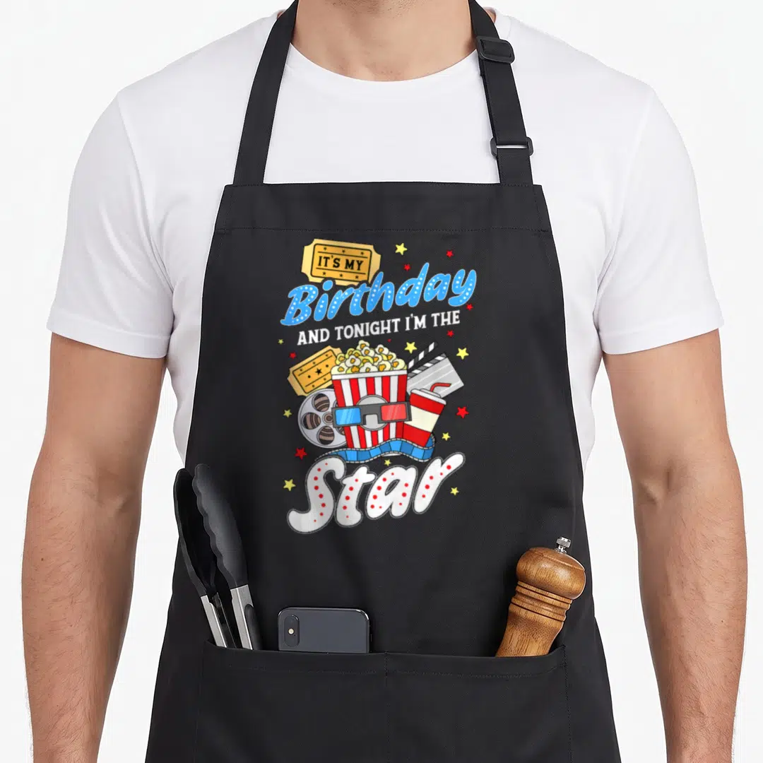 Movie night family aprons - Birthday Star text with popcorn, tickets, 3D glasses, and film reel in blue red yellow — shown on a black cotton canvas apron against a white background
