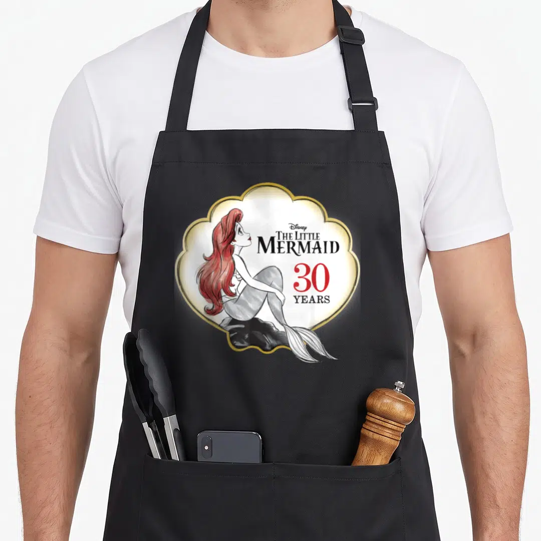 Anniversary mermaid apron - Ariel sitting on rock inside gold frame with 30 Years text — shown on a black cotton canvas apron against a white background