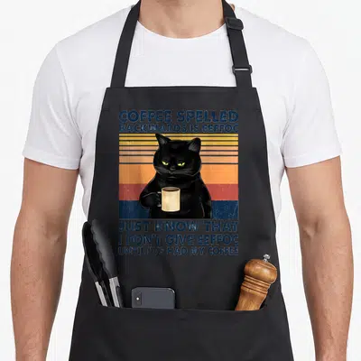 Spelled coffee apron - Retro black cat holding mug with eeffoc pun text on striped background — shown on a black cotton canvas apron against a white background