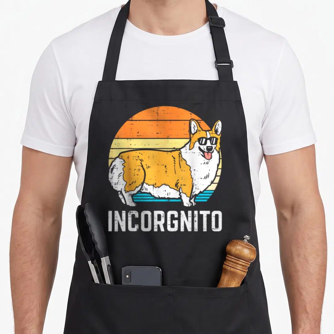 Incorgnito corgi aprons - Retro corgi in sunglasses before striped sun with INCORGNNITO text below — shown on a black cotton canvas apron against a white background