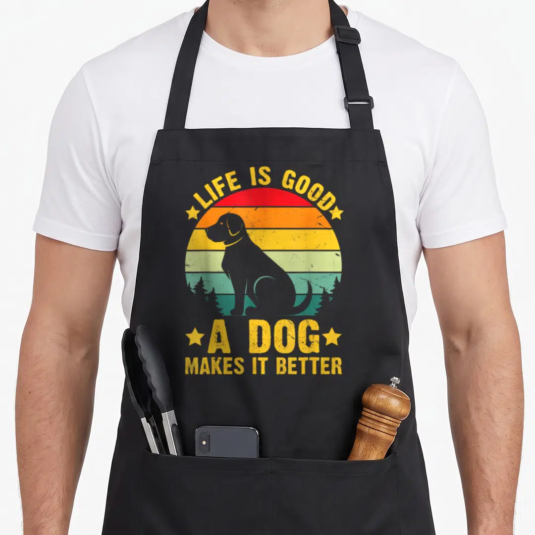 Cute better dog apron - Grey dog silhouette against yellow red orange teal striped sunset circle with yellow text — shown on a black cotton canvas apron against a white background