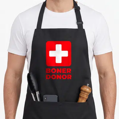 Boner halloween apron - White cross in red square above stacked red text reading BONER DONOR — shown on a black cotton canvas apron against a white background