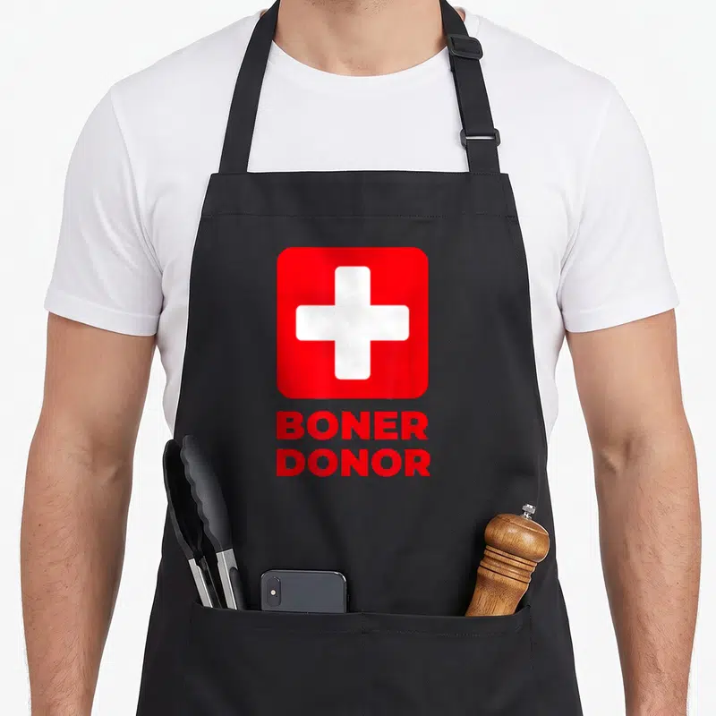 Boner halloween apron - White cross in red square above stacked red text reading BONER DONOR — shown on a black cotton canvas apron against a white background