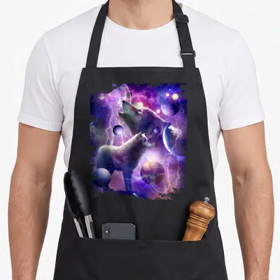 Wolf cosmic apron - Two wolves standing among planets and lightning bolts in purple and blue space art — shown on a black cotton canvas apron against a white background