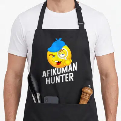 Hunter passover apron - Yellow smiley face in blue hat holding magnifying glass above white AFIKOMAN HUNTER text — shown on a black cotton canvas apron against a white background