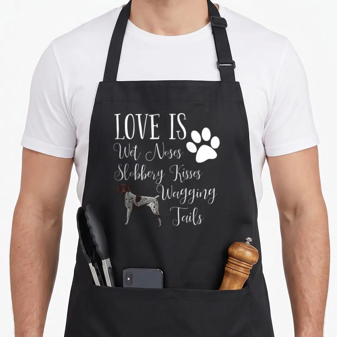 Shorthair dog pointer apron - White stacked text reading Love Is Wet Noses next to a brown and white spotted dog — shown on a black cotton canvas apron against a white background