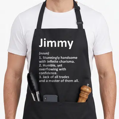 Christmas father day aprons - White text defining Jimmy as handsome and confident on black apron — shown on a black cotton canvas apron against a white background