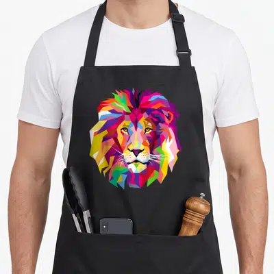 Elegant colorful apron - Multicolored geometric cartoon lion head face in red blue yellow green purple and pink — shown on a black cotton canvas apron against a white background