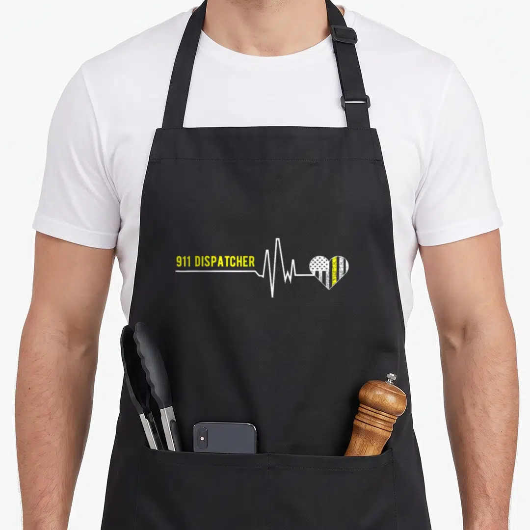 Funny dispatcher apron - 911 DISPATCHER text next to white heartbeat line ending in yellow striped heart — shown on a black cotton canvas apron against a white background