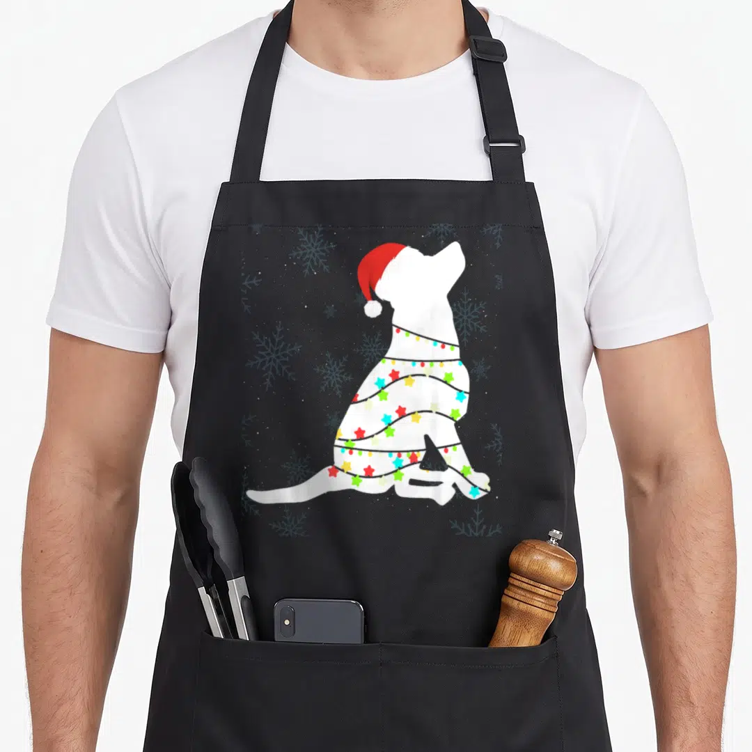 Labrador christmas lights apron - White dog silhouette wearing red santa hat and wrapped in star-shaped lights on grey — shown on a black cotton canvas apron against a white background