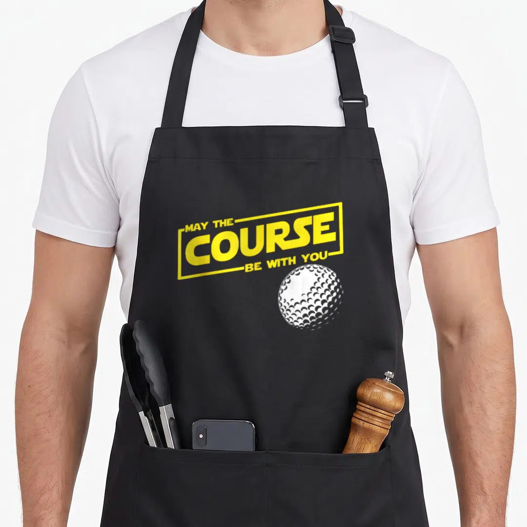 May golf apron - Yellow MAY THE COURSE BE WITH YOU text in rectangle frame above white golf ball — shown on a black cotton canvas apron against a white background