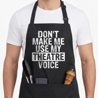 Use theater apron - White stacked text reading DON'T MAKE ME USE MY THEATRE VOICE with theatre in a white box — shown on a black cotton canvas apron against a white background