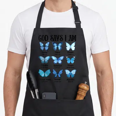 Butterfly god says i am apron - Nine blue watercolor butterflies with GOD SAYS I AM header and scripture references — shown on a black cotton canvas apron against a white background