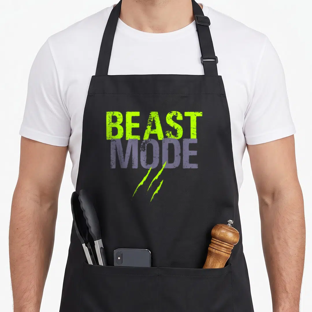 Beast workout motivation apron - Distressed BEAST MODE text in lime green and purple with three claw marks below — shown on a black cotton canvas apron against a white background