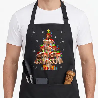 Cavapoo christmas tree apron - Triangle of brown puppies wearing Santa hats surrounded by colorful lights and gifts — shown on a black cotton canvas apron against a white background
