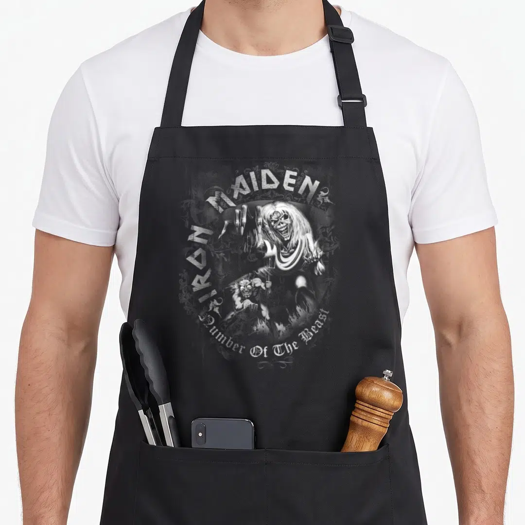 Beast number apron - Distressed white zombie and demon illustration with arched text and ornamental swirls — shown on a black cotton canvas apron against a white background