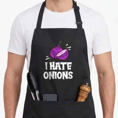 Hate onion lover apron - Cartoon purple onion and slice above white text I HATE ONIONS — shown on a black cotton canvas apron against a white background
