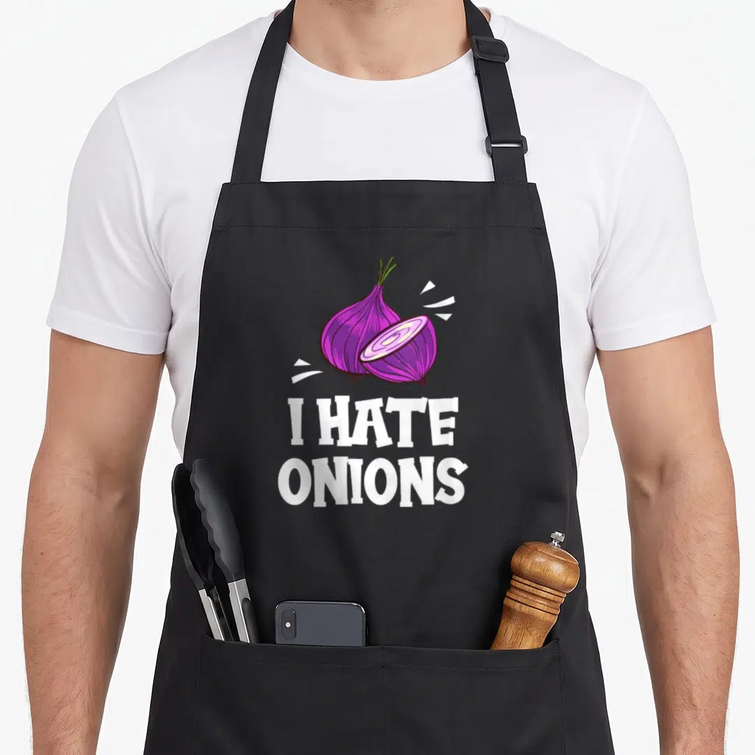 Hate onion lover apron - Cartoon purple onion and slice above white text I HATE ONIONS — shown on a black cotton canvas apron against a white background