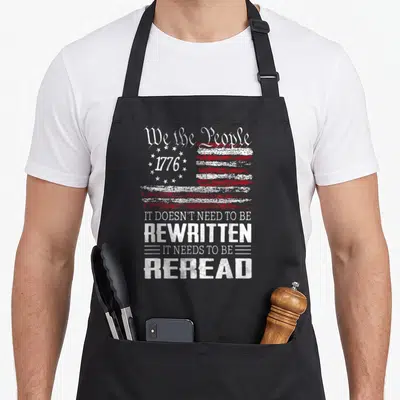Constitution us aprons - Distressed USA flag with We the People 1776 text and reread quote in white and red — shown on a black cotton canvas apron against a white background