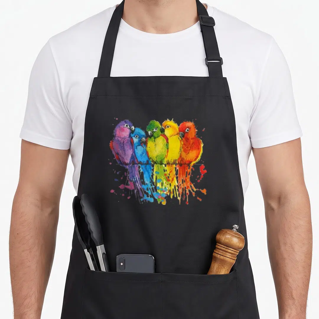 Colourful parrot bird apron - Five colorful parrots perched on a black line with watercolor splatters in purple, blue — shown on a black cotton canvas apron against a white background
