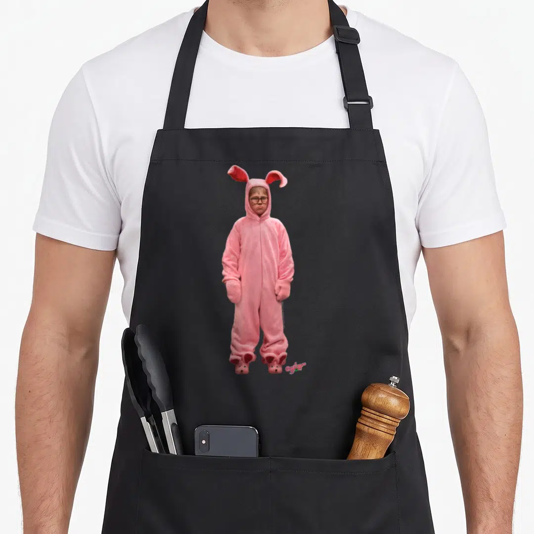 Christmas bunny apron - Child in pink bunny costume with A Christmas Story text logo — shown on a black cotton canvas apron against a white background