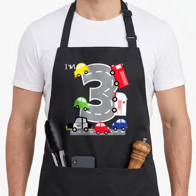 Transportation truck apron - Number 3 road design with toy police fire and emergency vehicles in cartoon style — shown on a black cotton canvas apron against a white background