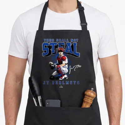 Shall ballpark mvp apron - Catcher illustration with Thou Shall Not Steal text and signature in blue red white — shown on a black cotton canvas apron against a white background