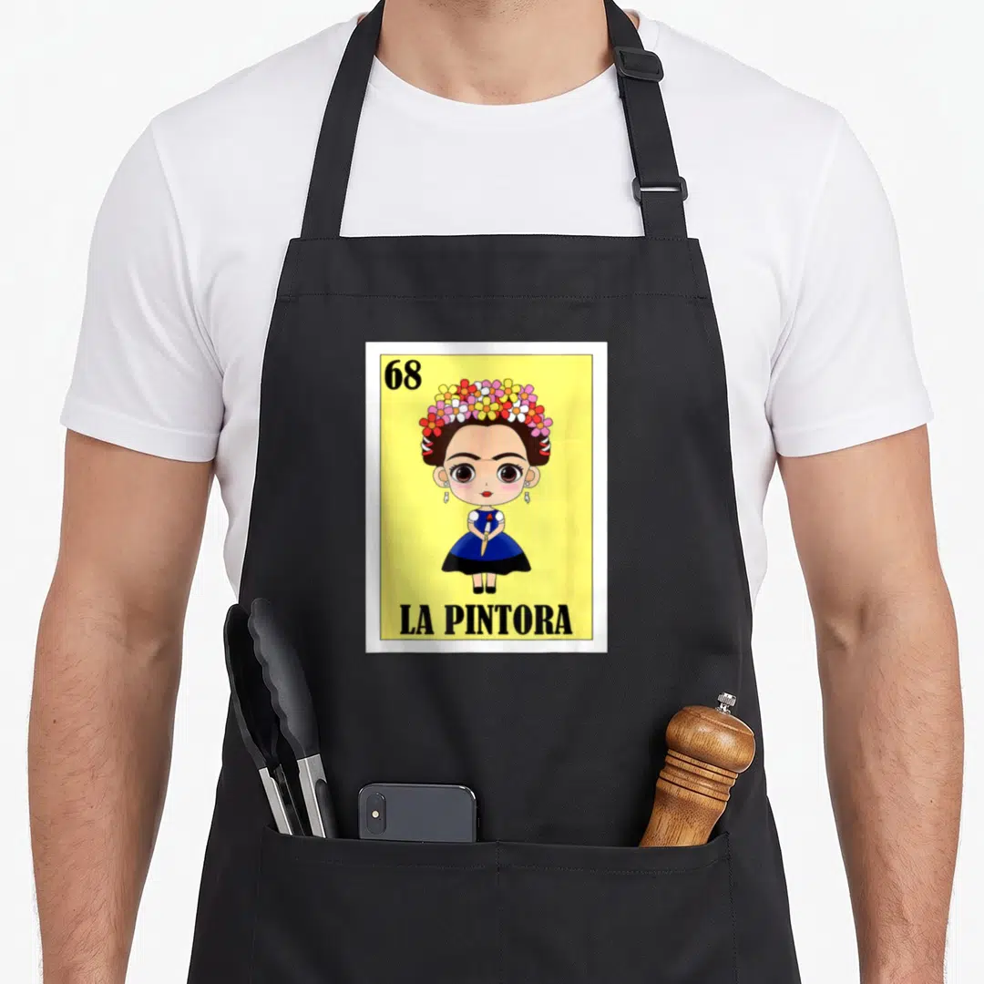 Pintora mexican apron - Cartoon woman with flower crown holding brush, text 68 LA PINTORA on yellow background — shown on a black cotton canvas apron against a white background