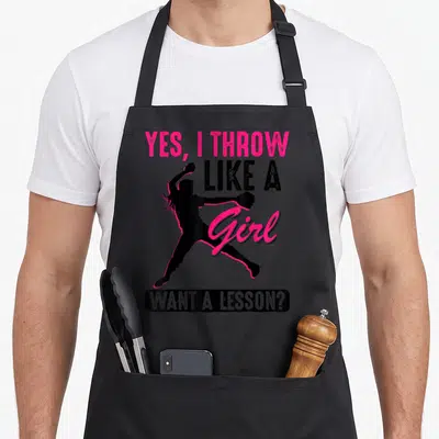 Throw yeah love apron - Softball pitcher silhouette with Yes I Throw Like A Girl Want A Lesson text — shown on a black cotton canvas apron against a white background