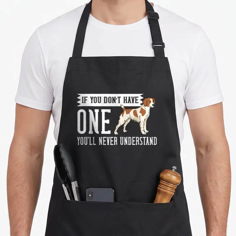 Spaniel french apron - Realistic brown and white spaniel standing next to white text IF YOU DON'T HAVE, ONE, YOU'LL — shown on a black cotton canvas apron against a white background