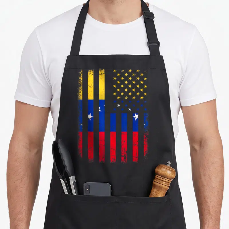 Venezuelan root american flag apron - Distressed vertical yellow blue red stripes and white and yellow stars on grey — shown on a black cotton canvas apron against a white background