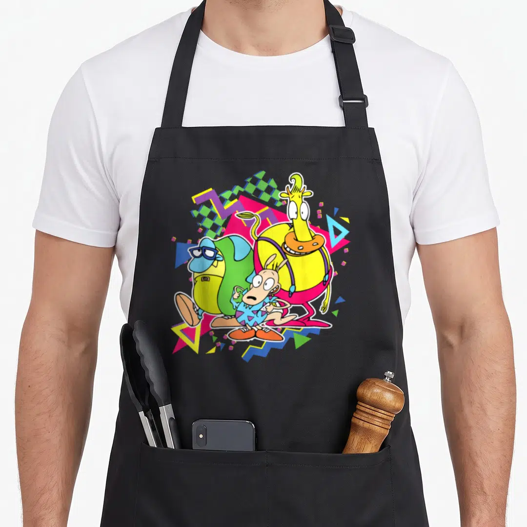 90s modern apron - Three cartoon monsters surrounded by yellow pink green blue purple geometric shapes and zigzags — shown on a black cotton canvas apron against a white background