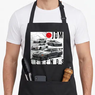 Backprint car apron - Three stacked JDM race cars with red circle and cracked white background — shown on a black cotton canvas apron against a white background