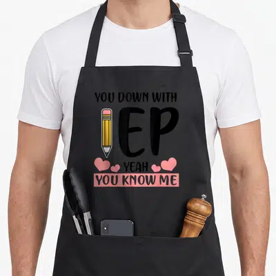Iep yeah teacher apron - Stacked YOU DOWN WITH IEP YEAH YOU KNOW ME text with pencil and pink hearts — shown on a black cotton canvas apron against a white background
