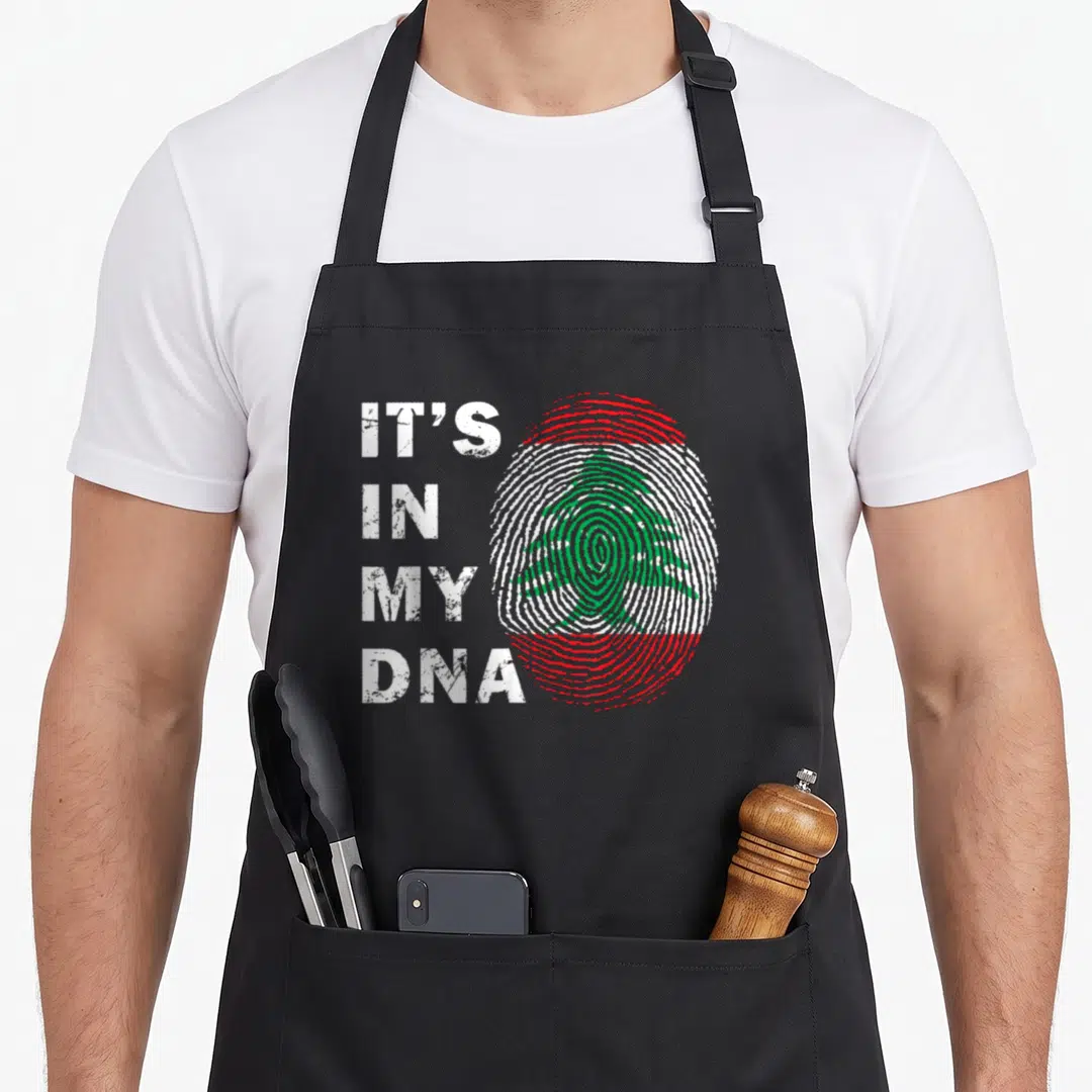 Lebanon lebanese girl apron - Fingerprint with green cedar tree and IT'S IN MY DNA text in red white green distressed — shown on a black cotton canvas apron against a white background