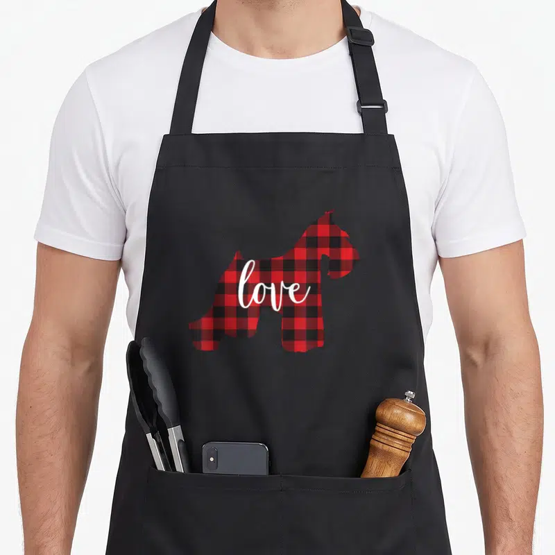 Schnauzer buffalo plaid apron - Red black buffalo plaid dog silhouette with white love script text — shown on a black cotton canvas apron against a white background