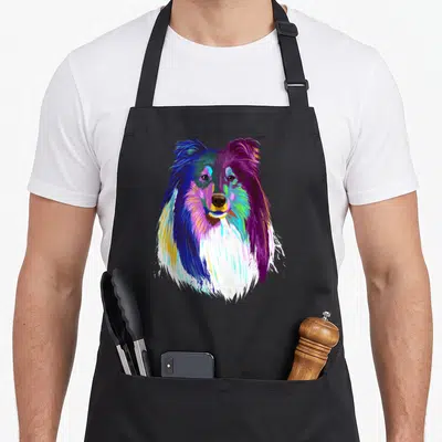 Colourful rough dog apron - Multicolored cartoon Rough Collie head in blue purple green yellow pink white on black — shown on a black cotton canvas apron against a white background