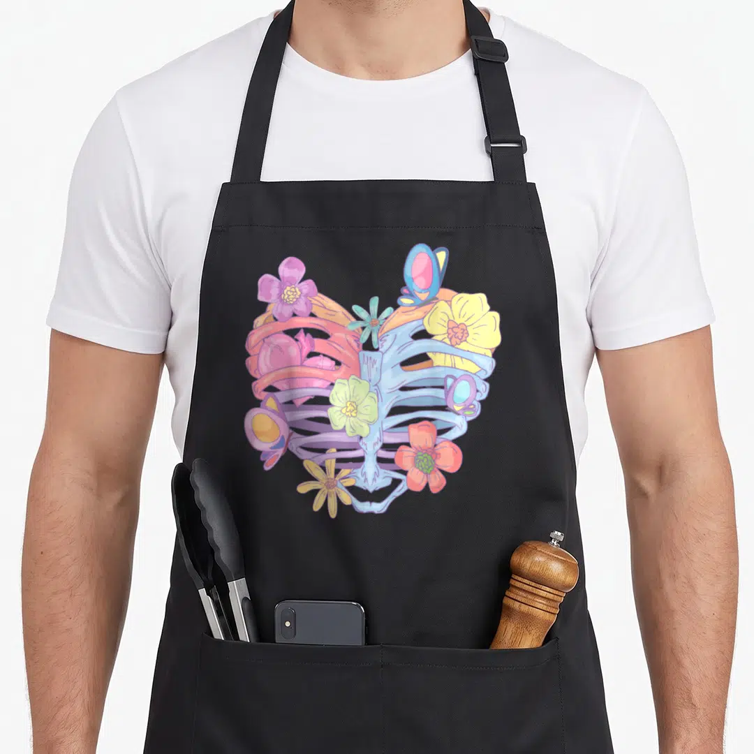 Pastel butterfly apron - Cartoon ribcage in blue purple yellow pink and red with flowers and butterflies — shown on a black cotton canvas apron against a white background